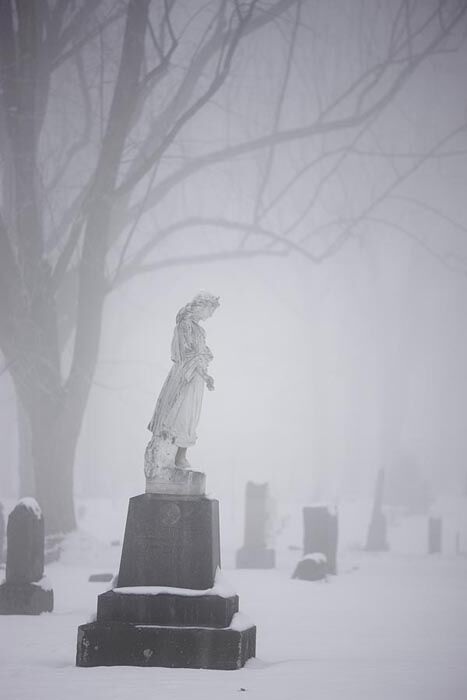 A statue of an angel is prominent among the surrounding gravestones. &nbsp;The fog and snow add to the absolute stillness of...